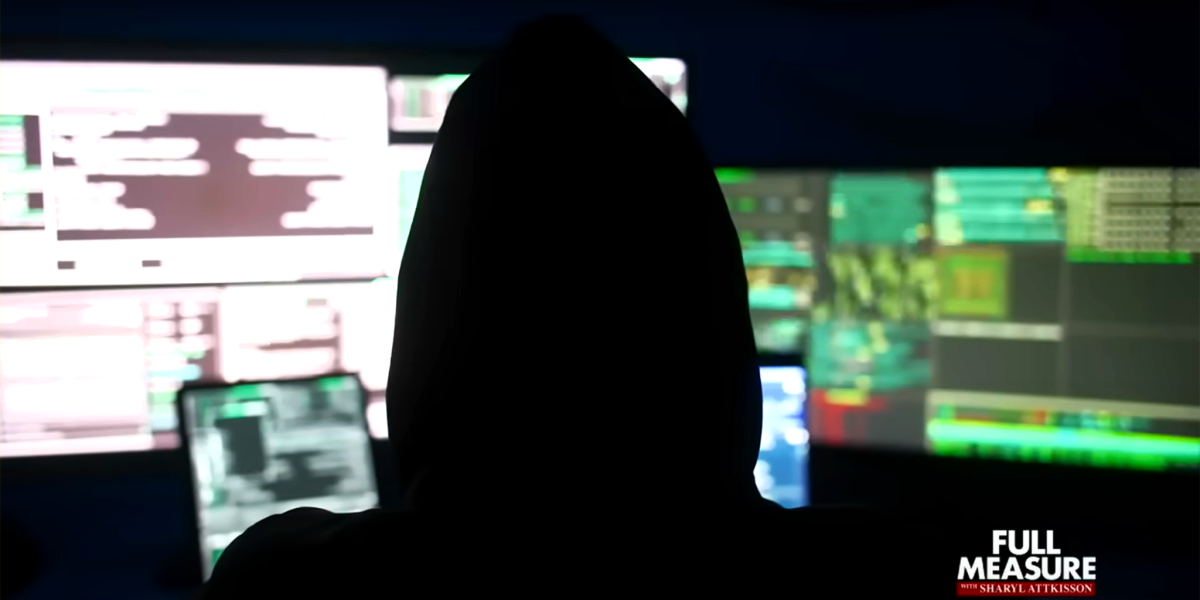 A silhouetted figure wearing a hood sits in the dark in front of a wall of glowing computer monitors. In the bottom right corner is a logo for "Full Measure with Sharyl Attkisson".